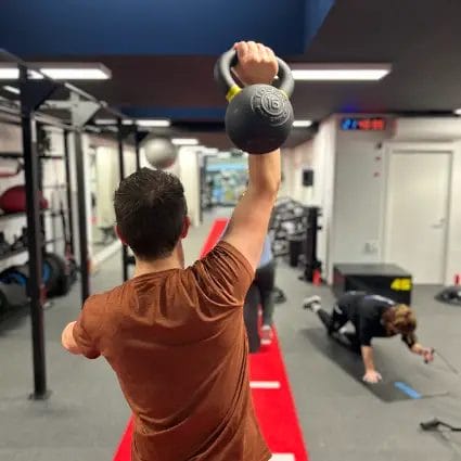 Athlete performing kettlebell overhead exercise during functional training at SHARP GYM